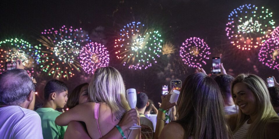 Queima de fogos sobre a orla de Copacabana durante o Réveillon, com multidão na areia